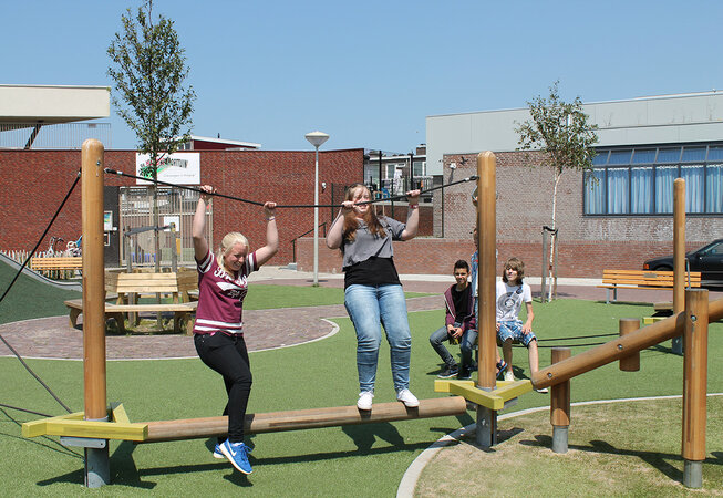 Schulhofplanung – Eine Gruppe Jugendlicher balanciert über eibe Spielgeräte auf dem Pausenhof.