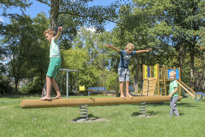 Schulhofplanung – Drei Jungs balancieren über eibe Spielgerät auf ihrem Pausenhof.